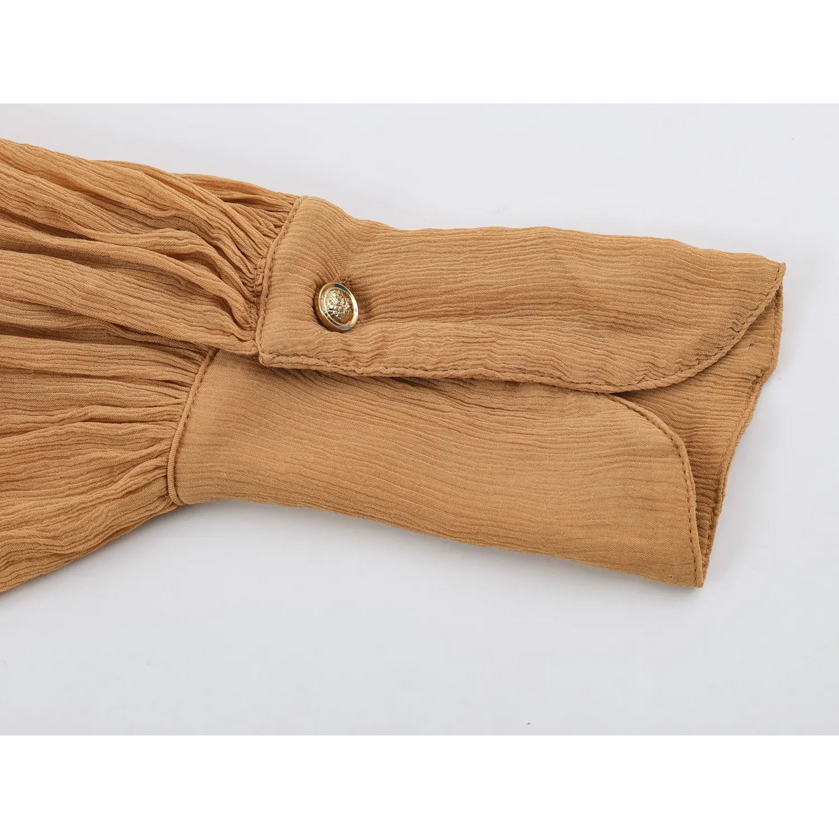 Close‑up of balloon sleeve cuff with engraved metallic button