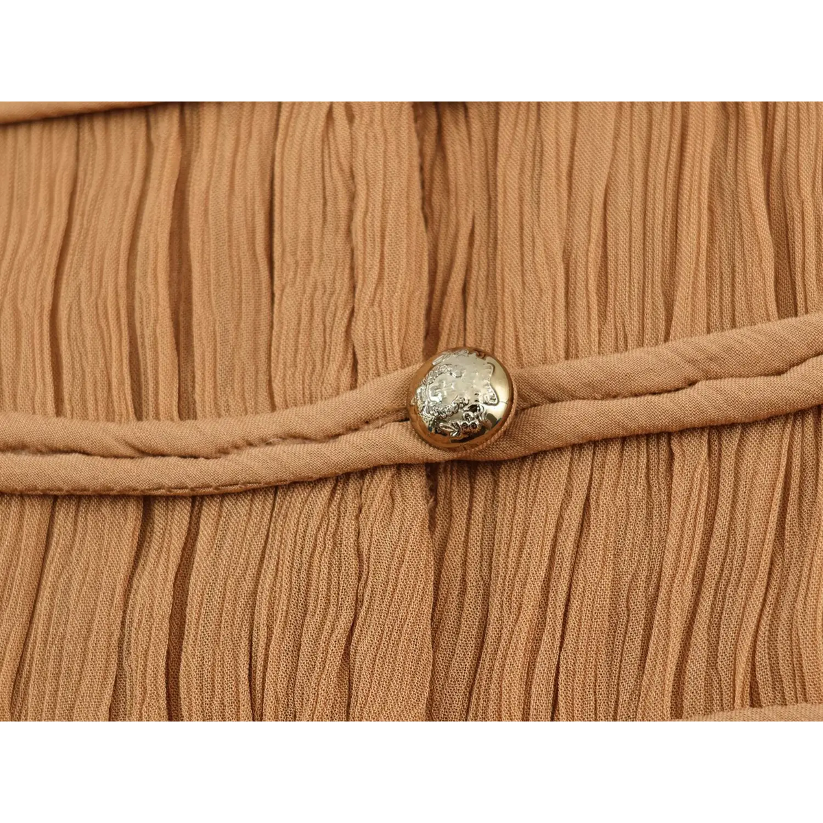 Macro shot of decorative frog knot and engraved metal button on camel maxi dress