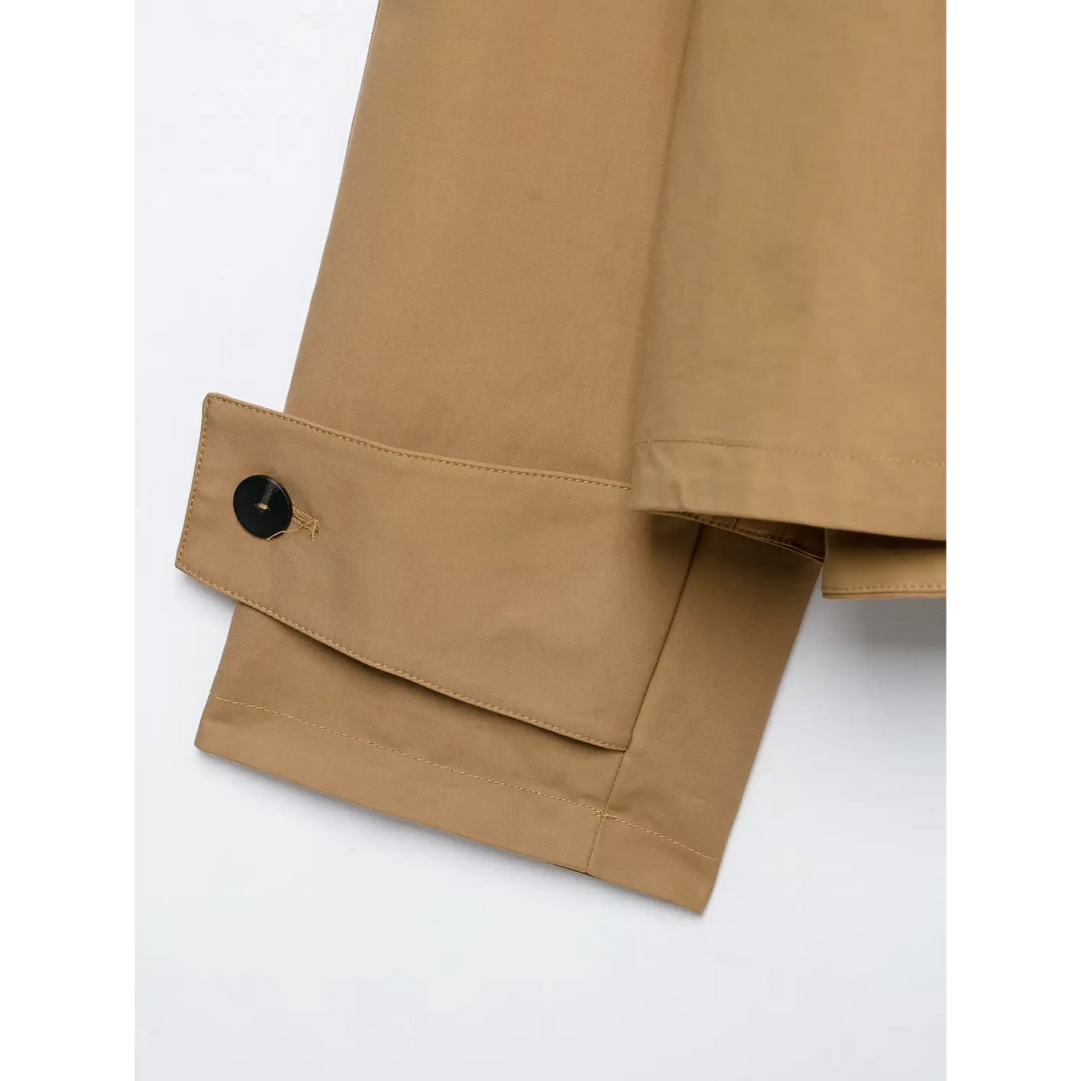 Detail shot of camel jacket folded sleeve cuff with single black button and fine stitching