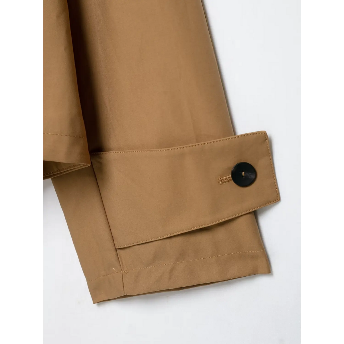 Close-up view of camel cropped jacket folded sleeve cuff with black round button and neat stitching
