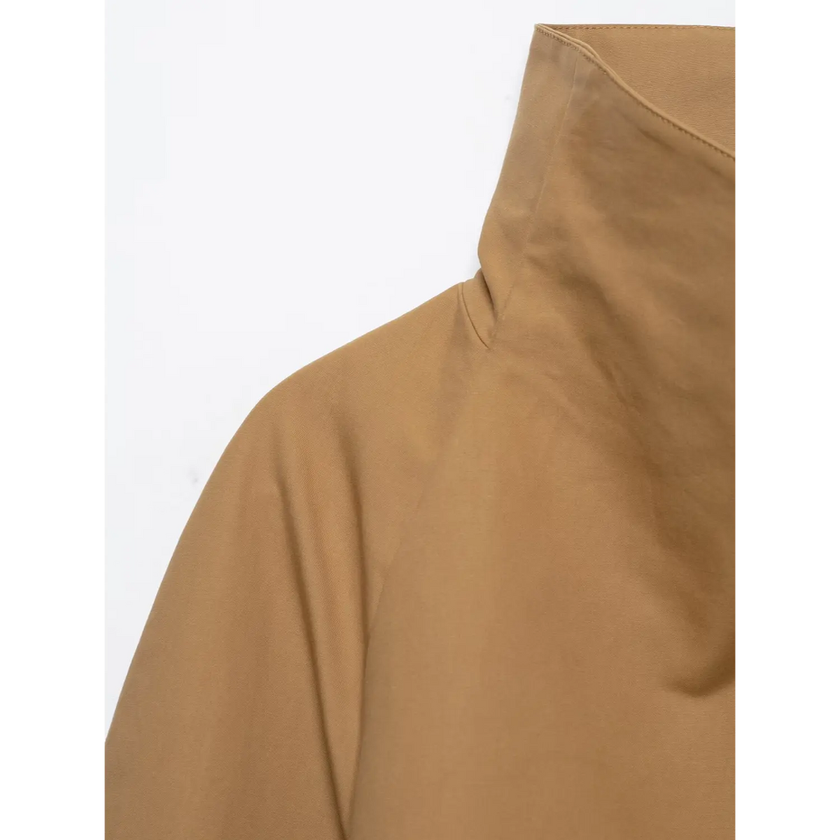 Close-up of camel cropped jacket, asymmetric folded high collar and raglan shoulder detail