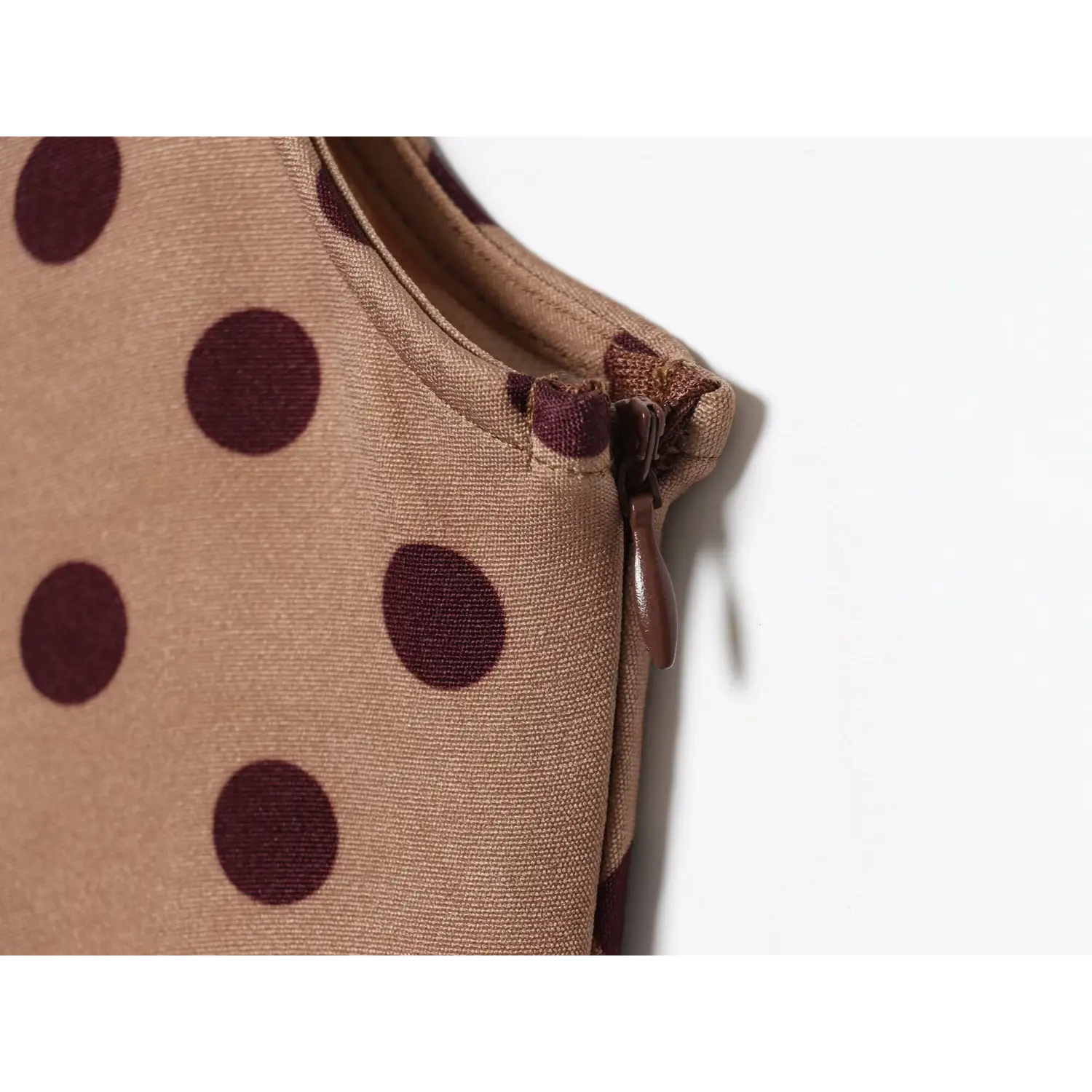 Close-up shot of concealed side zipper on camel brown dark polka dot sleeveless midi dress