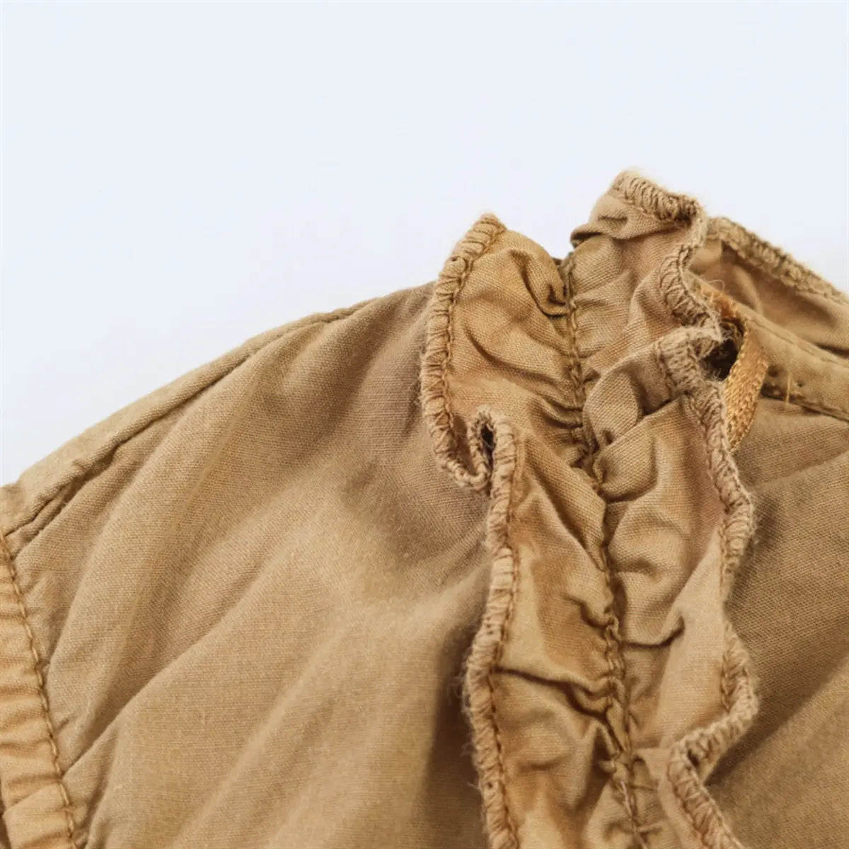 Close-up of the ruffled sleeve and gathered fabric detail on the camel-colored bodice top