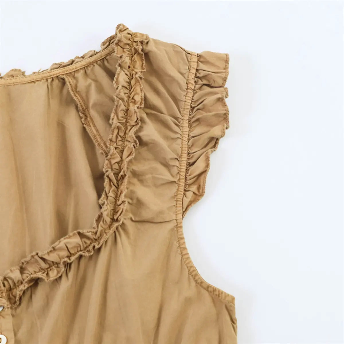Close-up of the ruffled sleeve and gathered fabric detail on the camel-colored bodice top