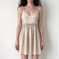 Model wearing camel tie strap babydoll ruffle waist mini dress, front view