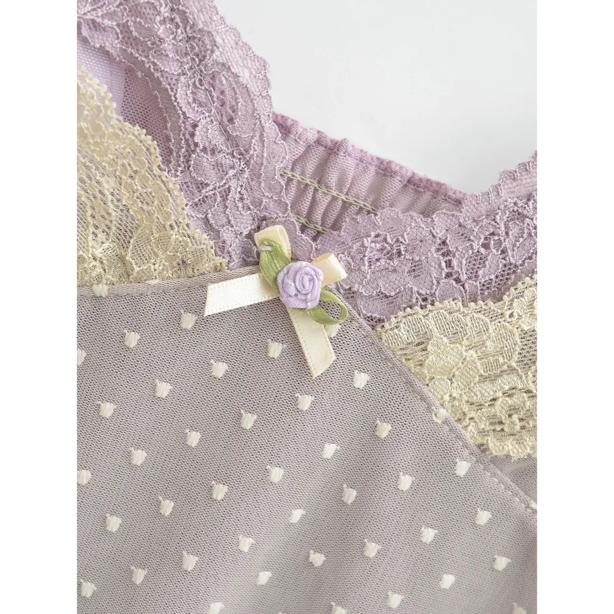 Close-up of the lace-trimmed neckline and the small lavender rose accent at the center front.