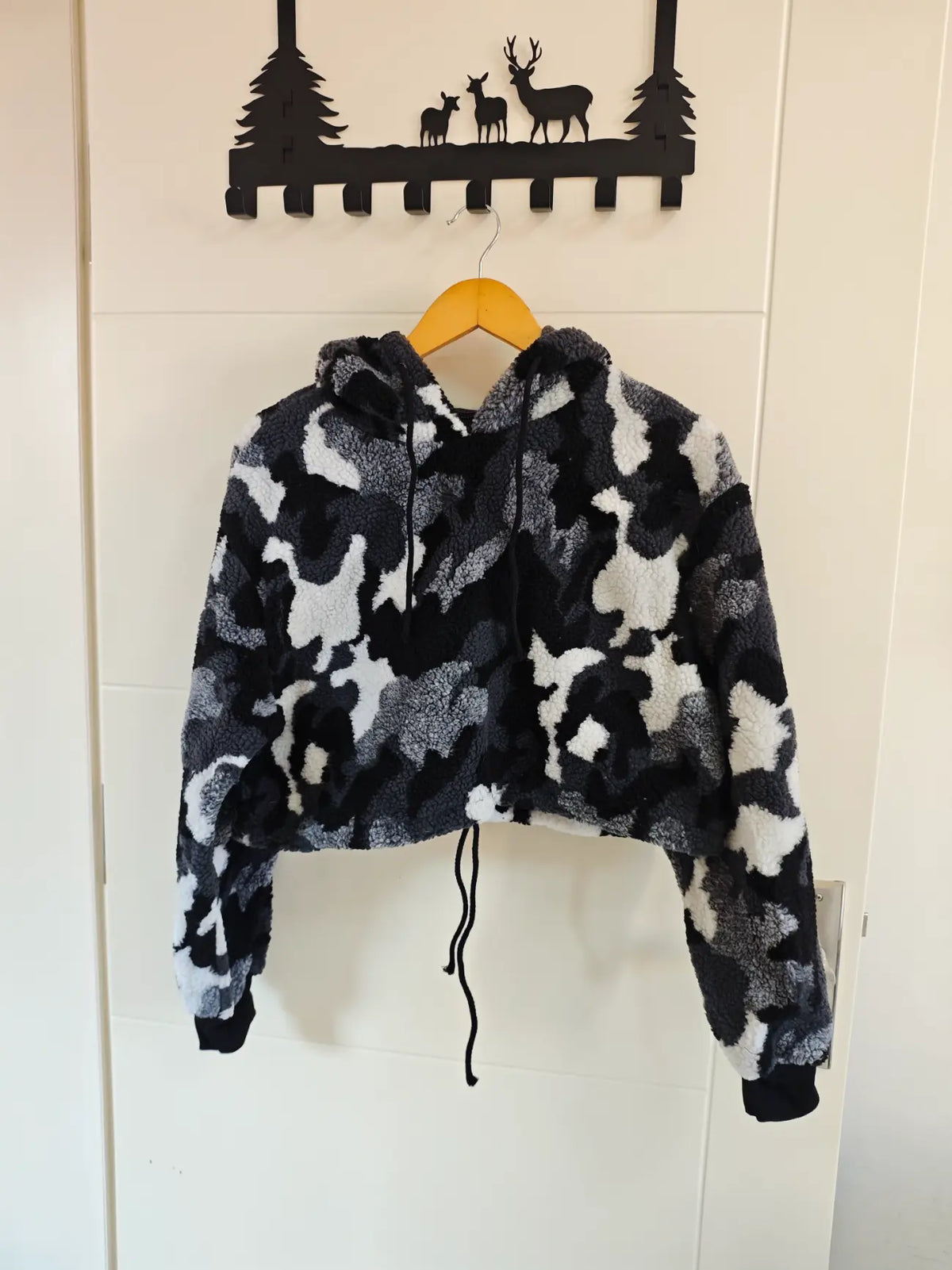 Camouflage teddy fleece hooded cropped hoodie hanging on door, front view