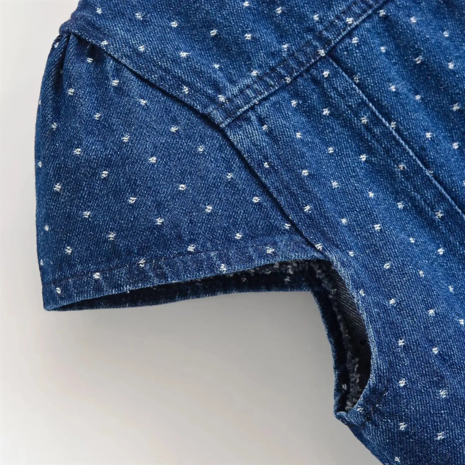 Short cap sleeve cuff close-up, narrow folded cuff binding, side panel vertical stitching, washed denim soft crease texture
