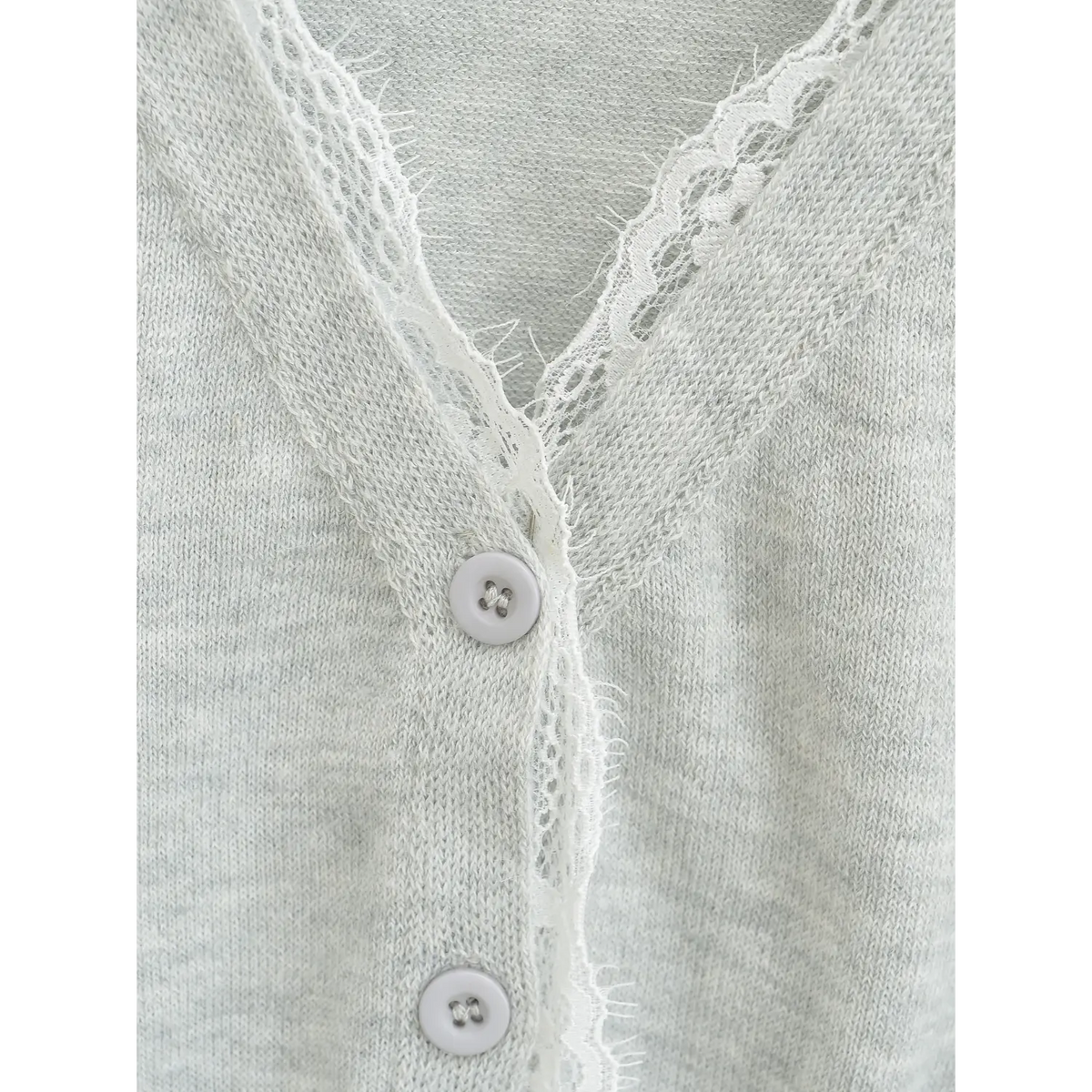 Extreme close-up of front button and lace trim, round matching button attached on knit placket