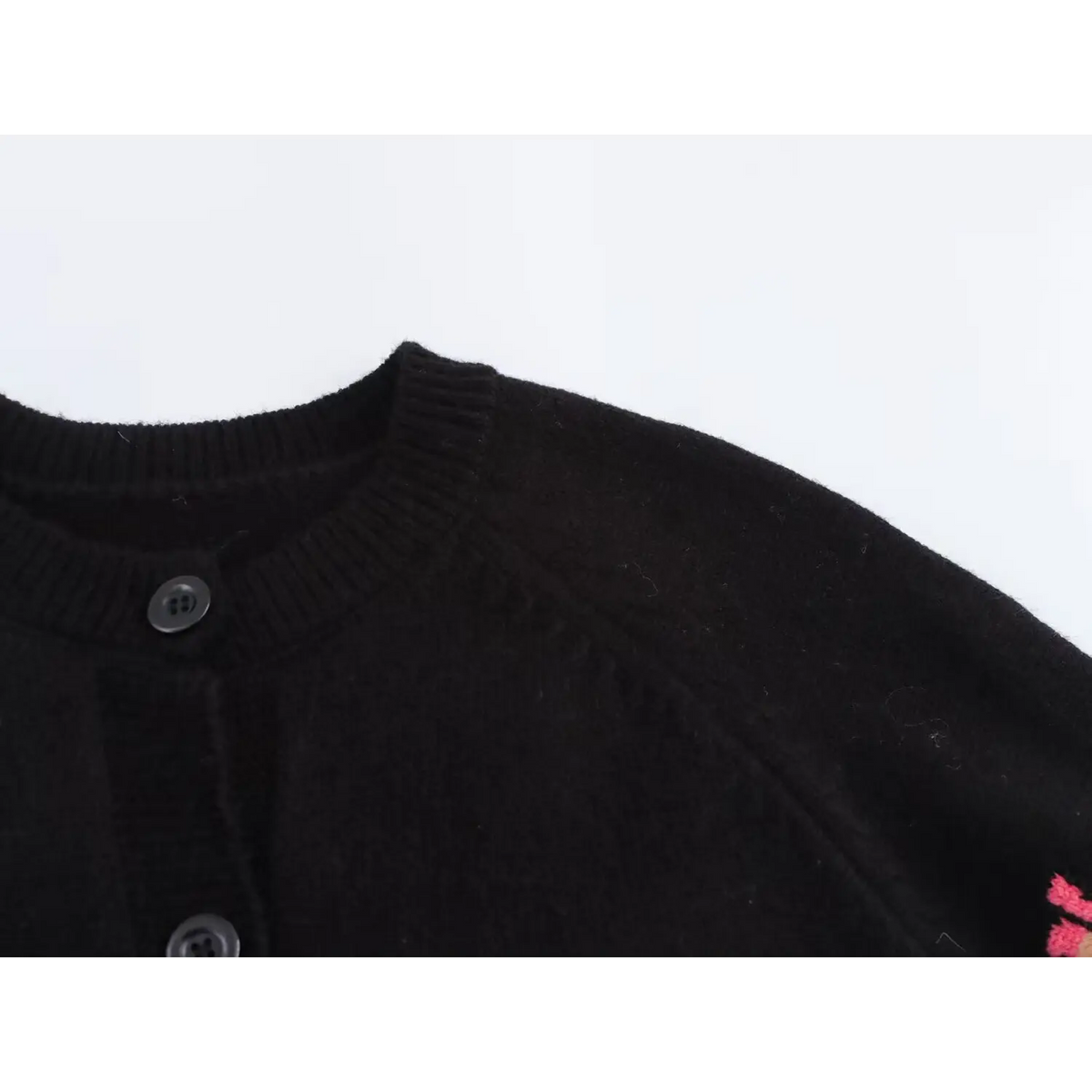 Close-up of ribbed crew neck and shoulder button
