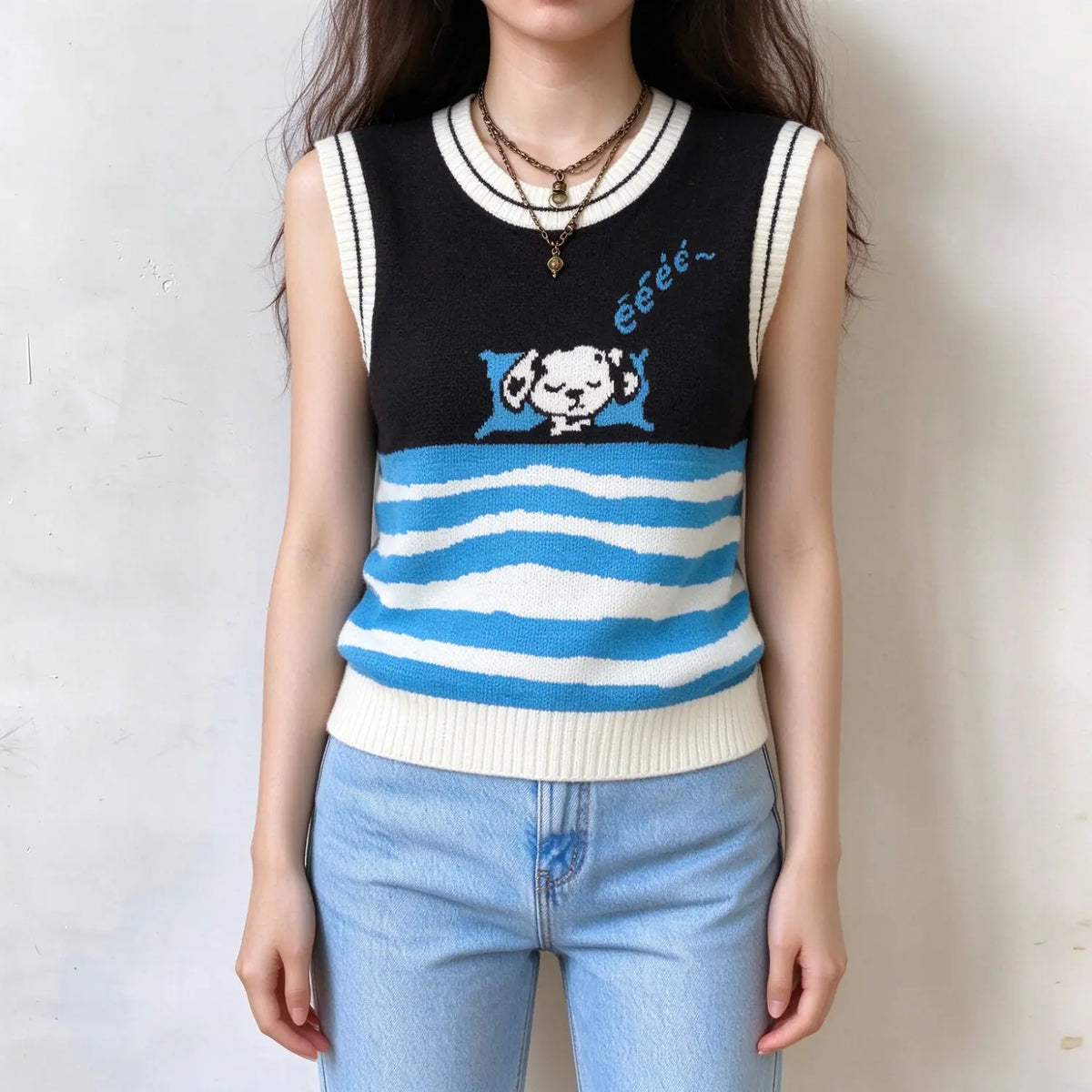 Female model wears sleeveless knit vest, black top with cute sleeping cartoon dog graphic, blue and white wavy stripe hem, white trim on crew neck and armholes, front full torso shot