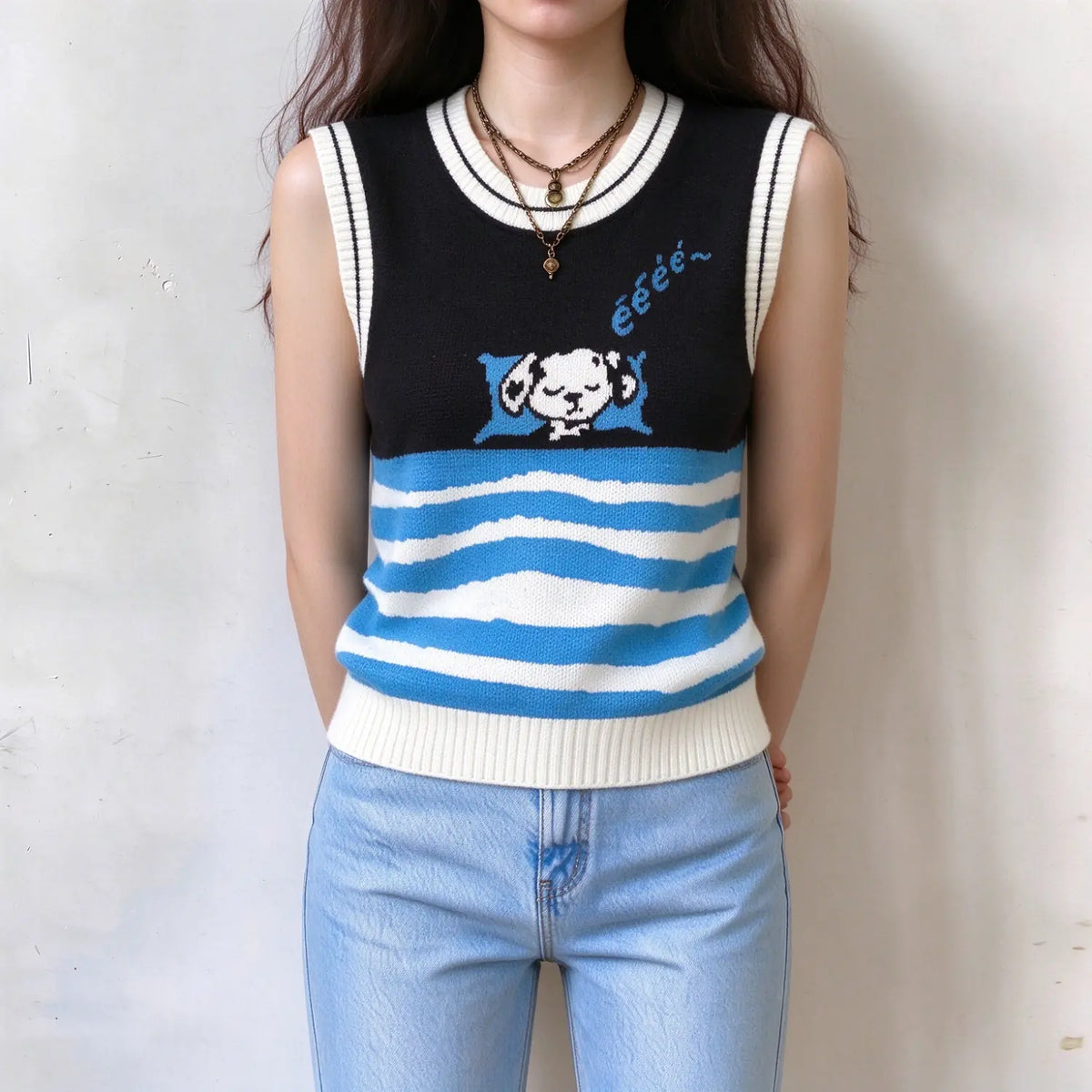 Female model wearing ladies sleeveless knitted waistcoat, front cartoon sleeping dog print, blue white irregular stripe lower part, model hands behind back display