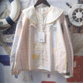 Macaron cartoon strip print sailor collar long sleeve blouse wooden hanger shot, cream double layer sailor lapel blue pink contrast piping trim symmetrical shoulder light blue & pink tiny bows front white round buttons cuff long sleeve japanese kawaii loose printed shirt hero shot
