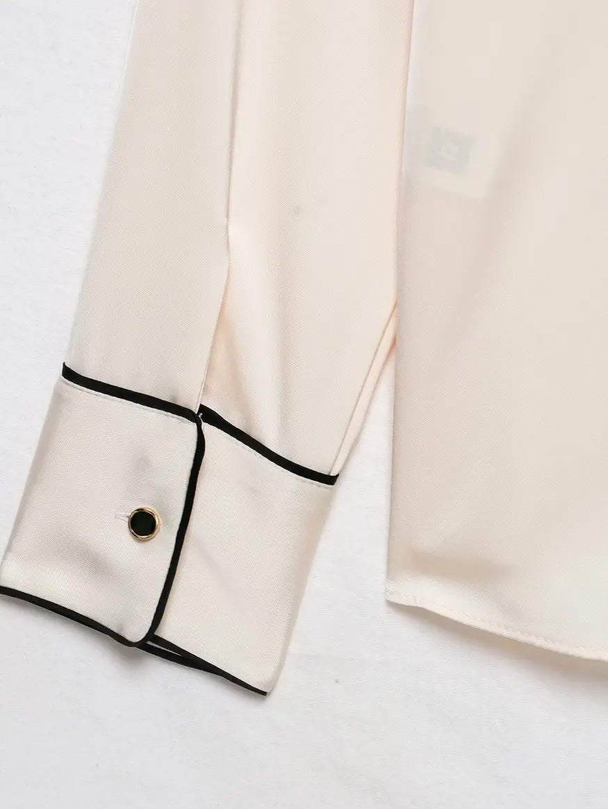 Close-up of black piping cuff with gold rim button