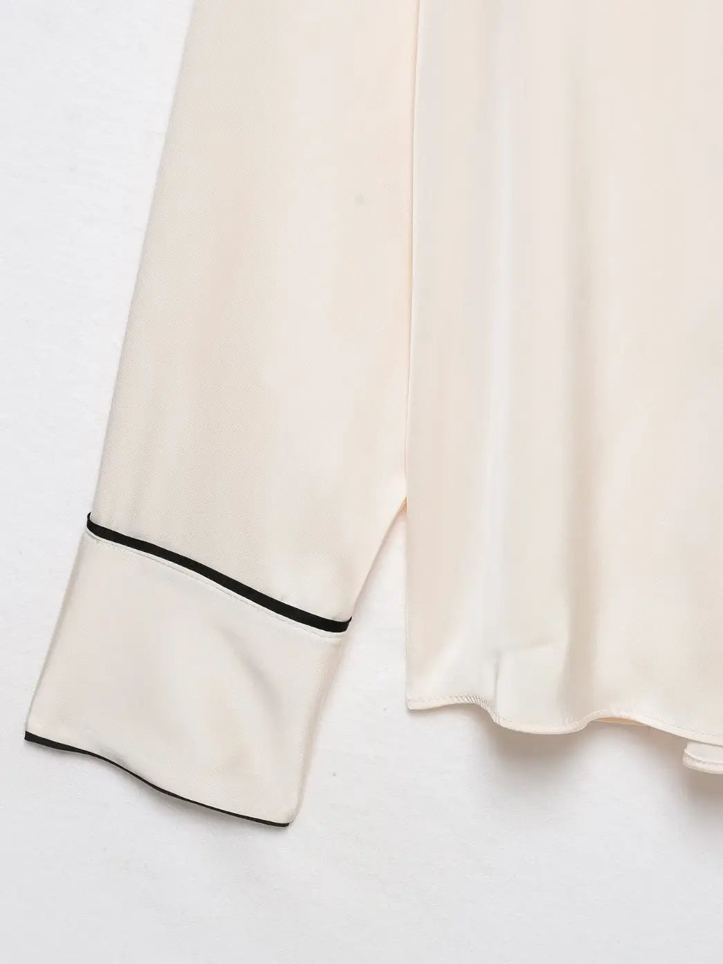Close-up of black piping cuff and curved hem