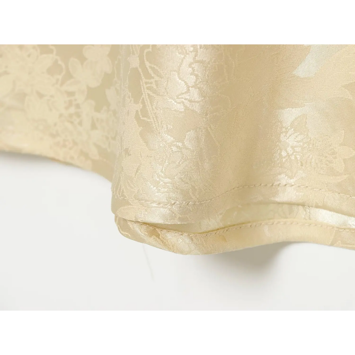 Close-up of finished hem stitching on champagne satin dress