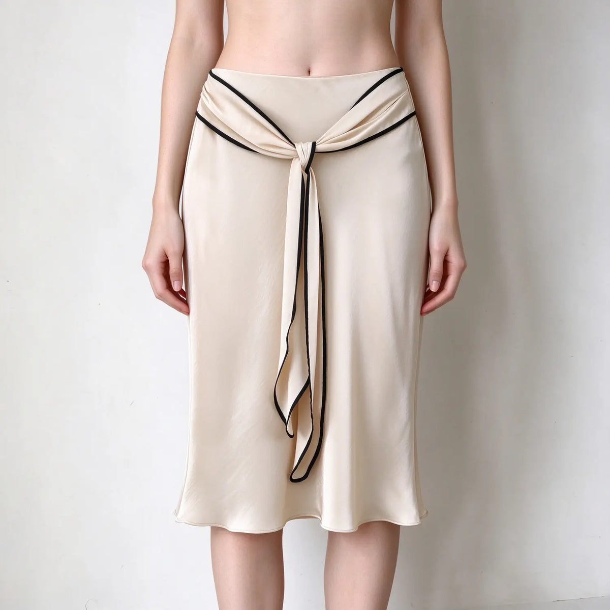 Model wearing champagne twist front satin slip midi skirt, front view