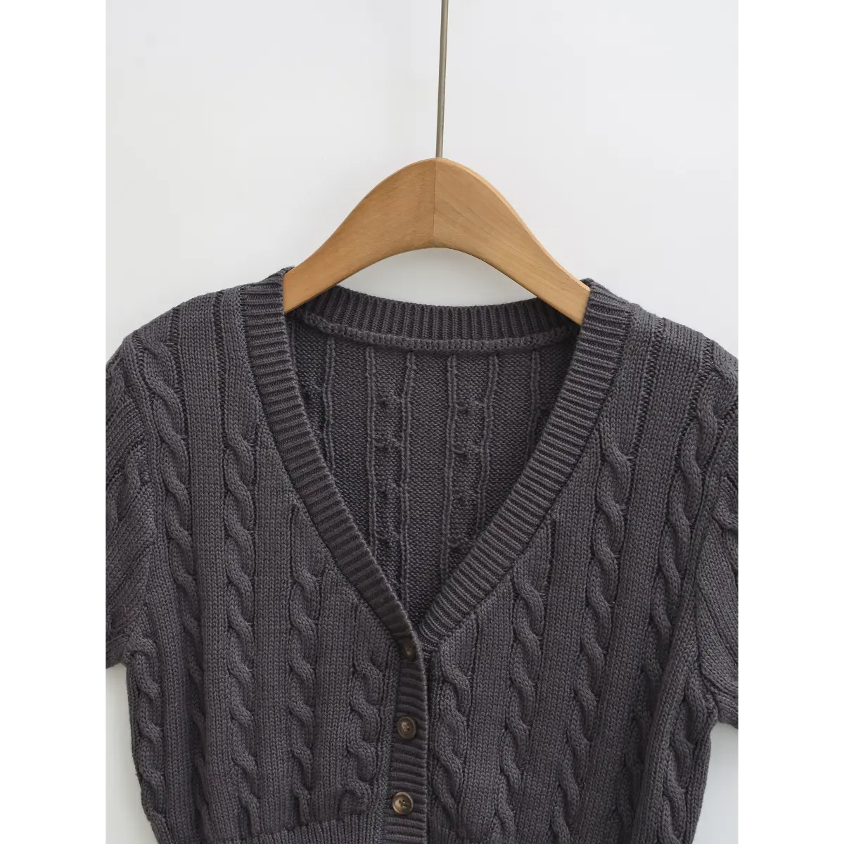 Full front studio shot of the charcoal gray cable knit short-sleeve cardigan, showing the V-neck and button placket.