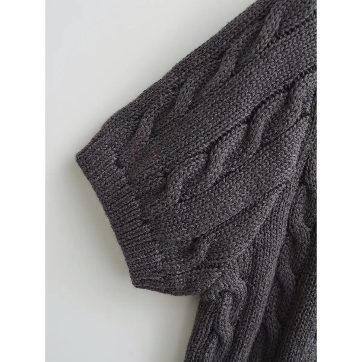 Close-up of the short ribbed cuff and intricate cable knit pattern on the sleeve.