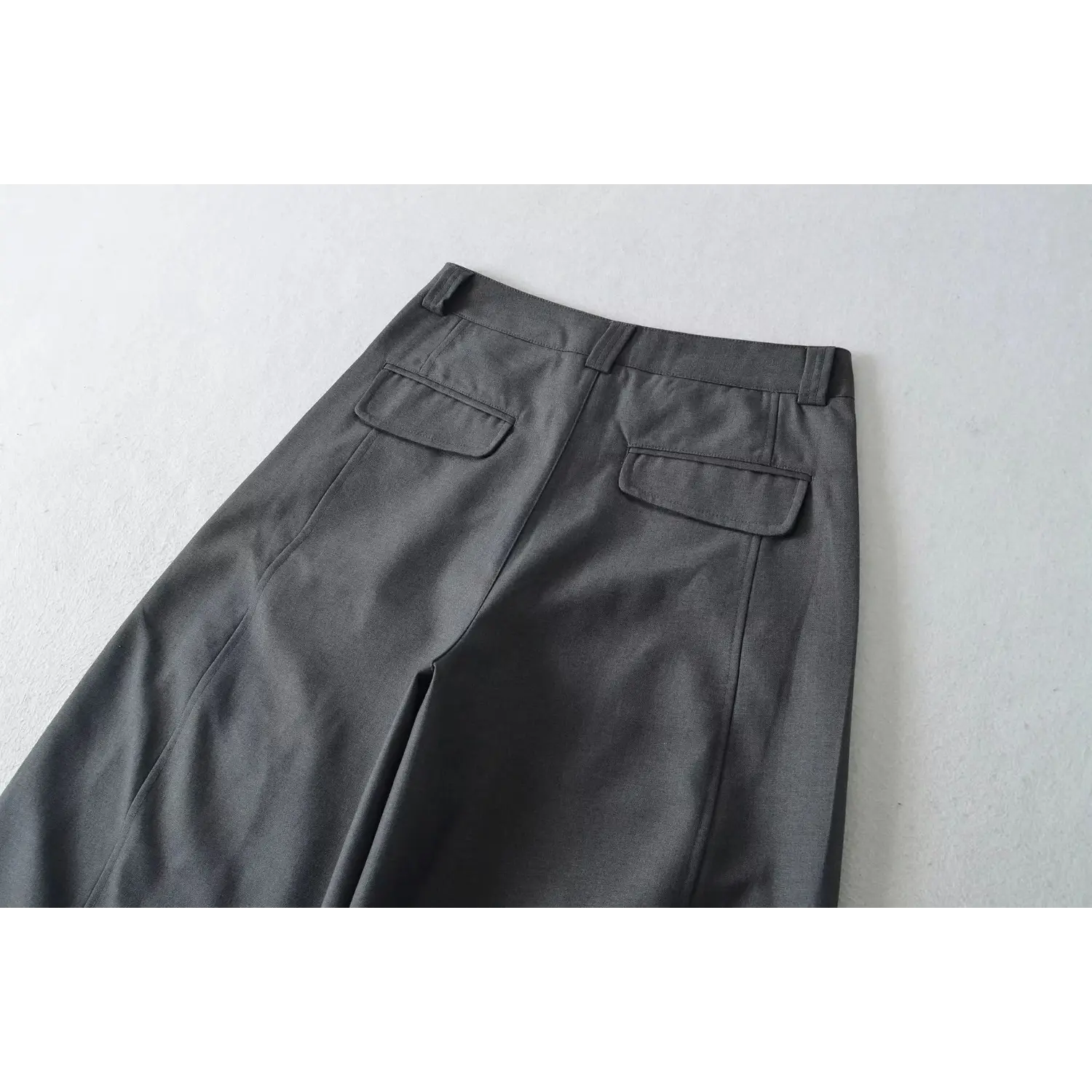 Back view flat lay of charcoal gray wide leg dress pants, highlight double patch back pockets, waistband and side seam construction