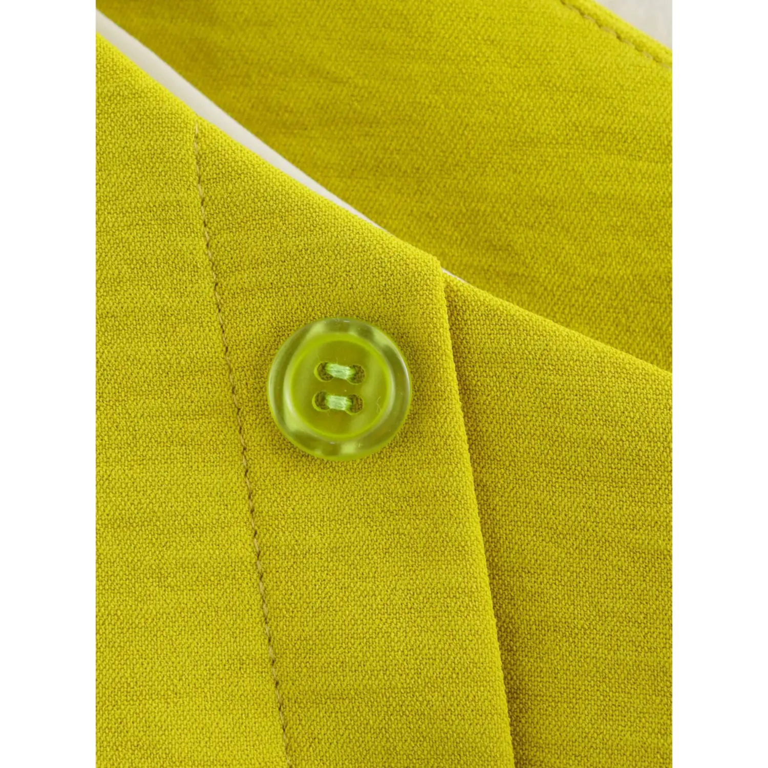 Macro shot of translucent green matching button on chartreuse single shoulder vest