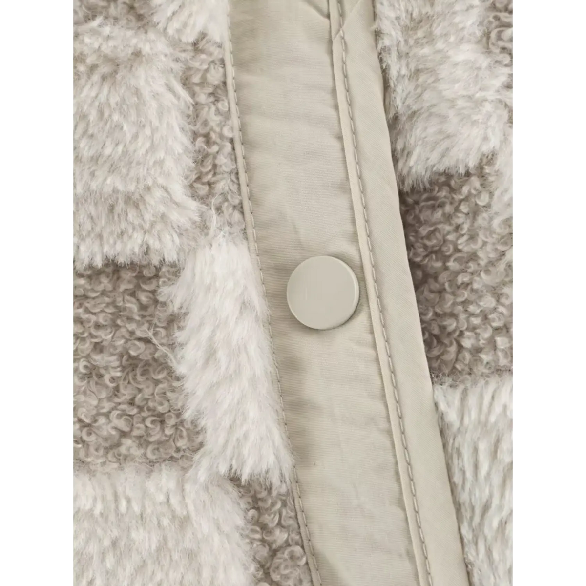 Detailed shot of round snap button and stitching on beige checkered faux fur outerwear
