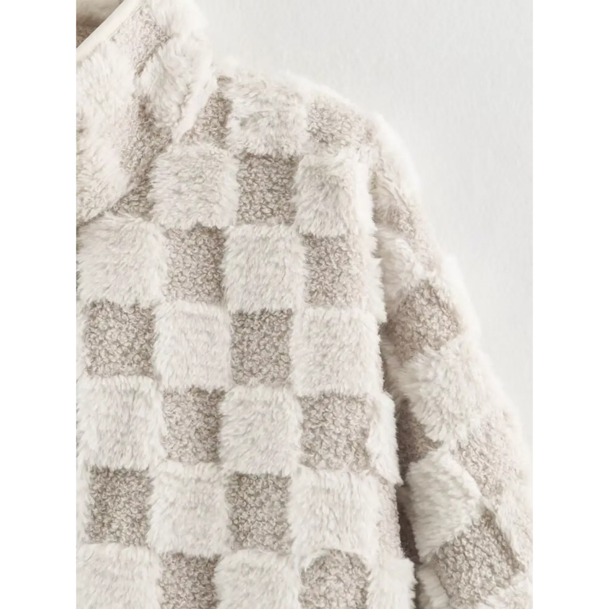 Macro shot of mixed texture fabric, fluffy faux fur and curly sherpa checker pattern jacket