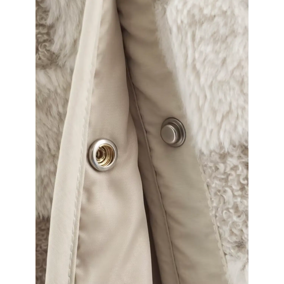 Macro shot of metal snap buttons and stitching on placket of checkered fuzzy fur outerwear