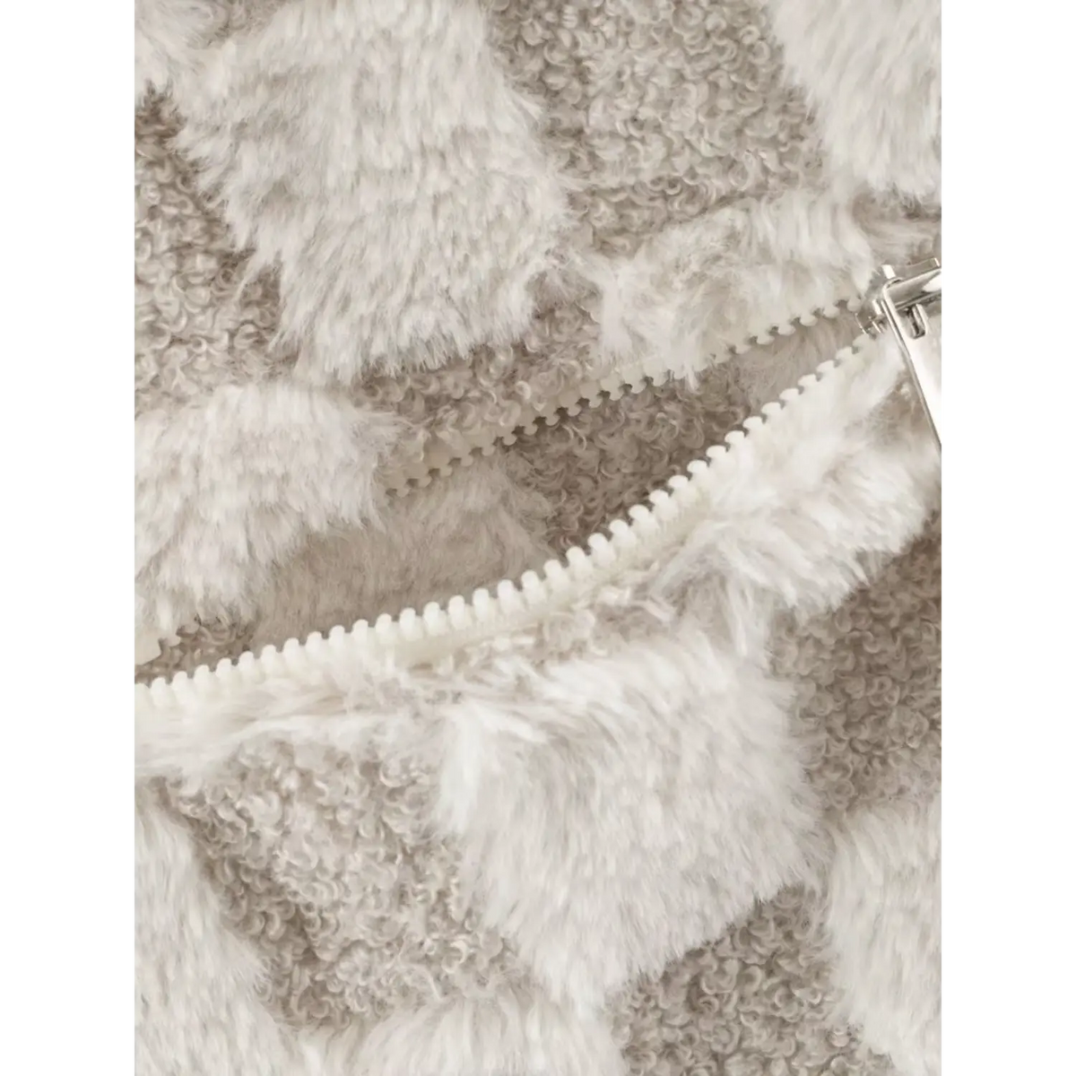 Close up of zipper pocket on beige white checkered faux fur jacket, fluffy checkerboard fabric and metal zipper pull