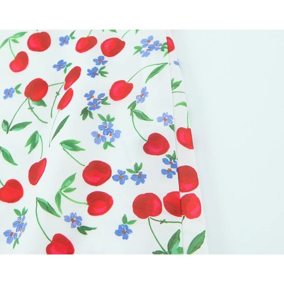 Close-up of the lightweight fabric, showing the cherry and blue floral print.