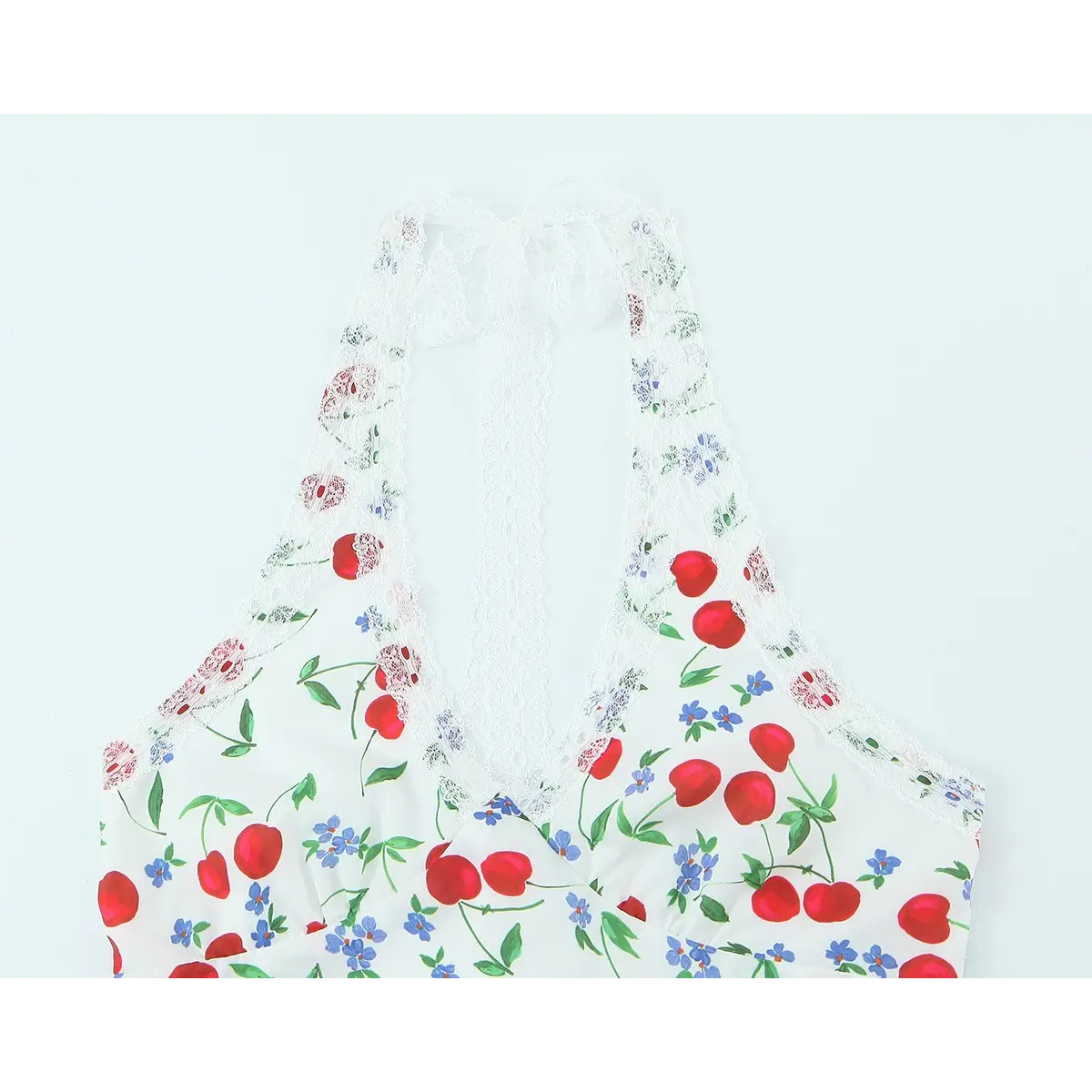 Close-up of the halter neckline, delicate lace trim, and cherry print on the white dress.