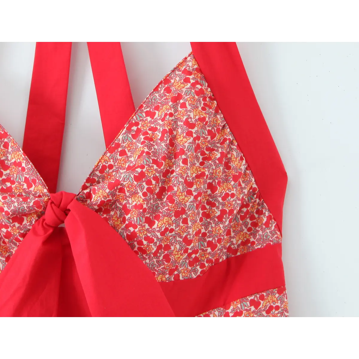 Close-up of red overlock stitching inside the cherry floral dress, showing fine workmanship of garment seams.