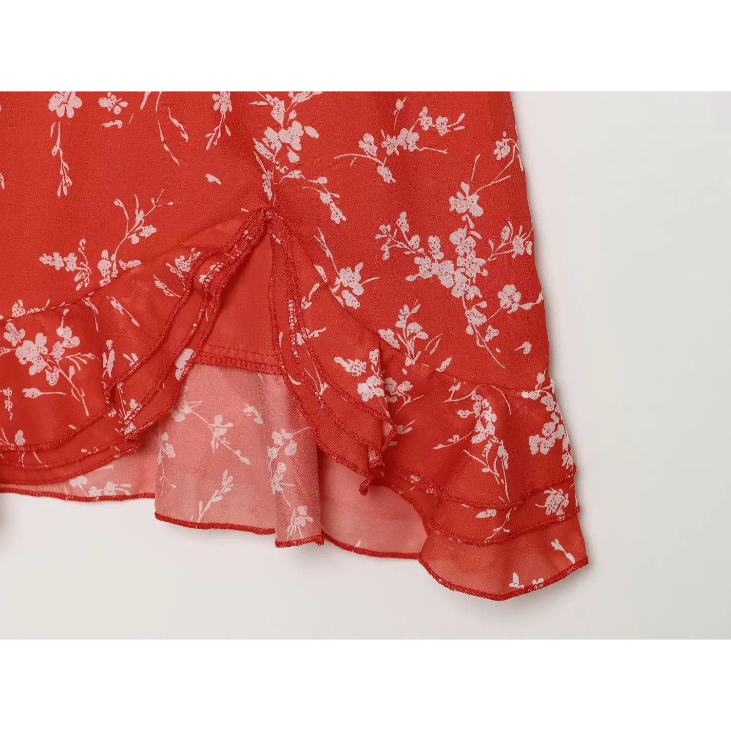 Extreme close-up of double layered ruffled hem and lining of red floral mini dress