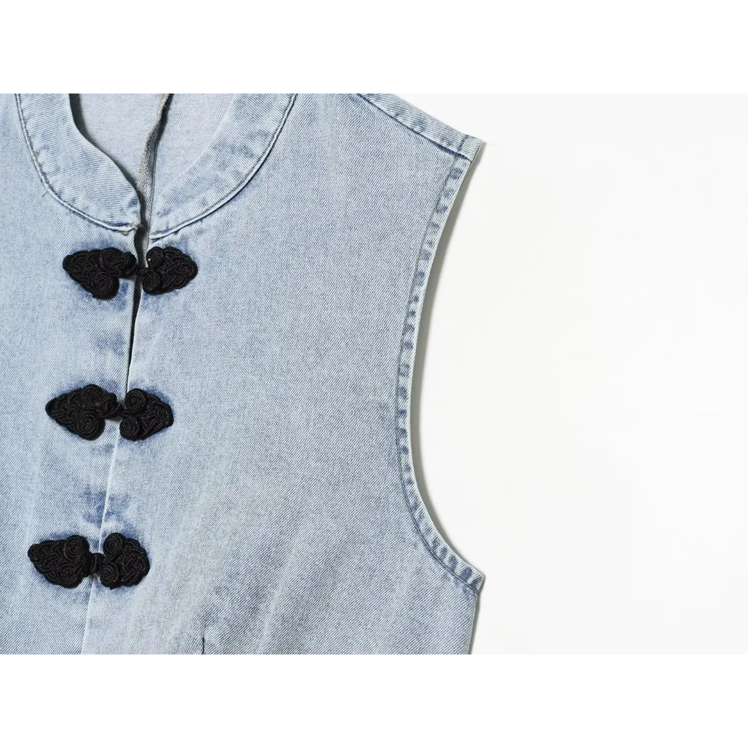 Closeup contrast black embroidery frog buttons and denim side shaping seams