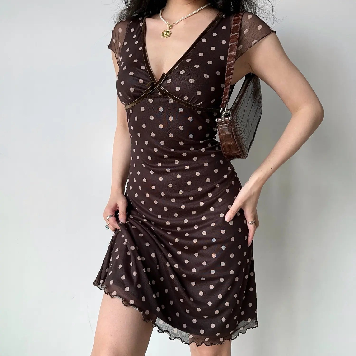 Model front pose chocolate brown polka dot mesh midi dress v‑neck velvet trim small bow cap sleeve lettuce ruffle hem bodycon silhouette