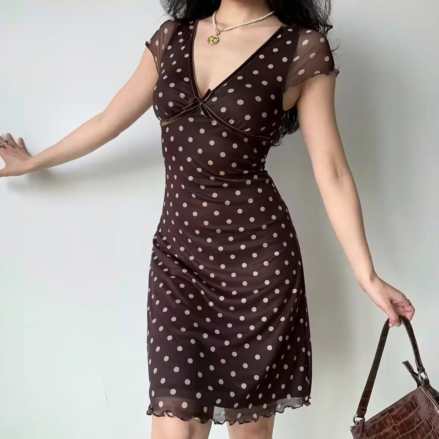 Model front stretch pose chocolate brown polka dot mesh midi dress deep v‑neck velvet piping short mesh cap sleeve fitted ruffle hem