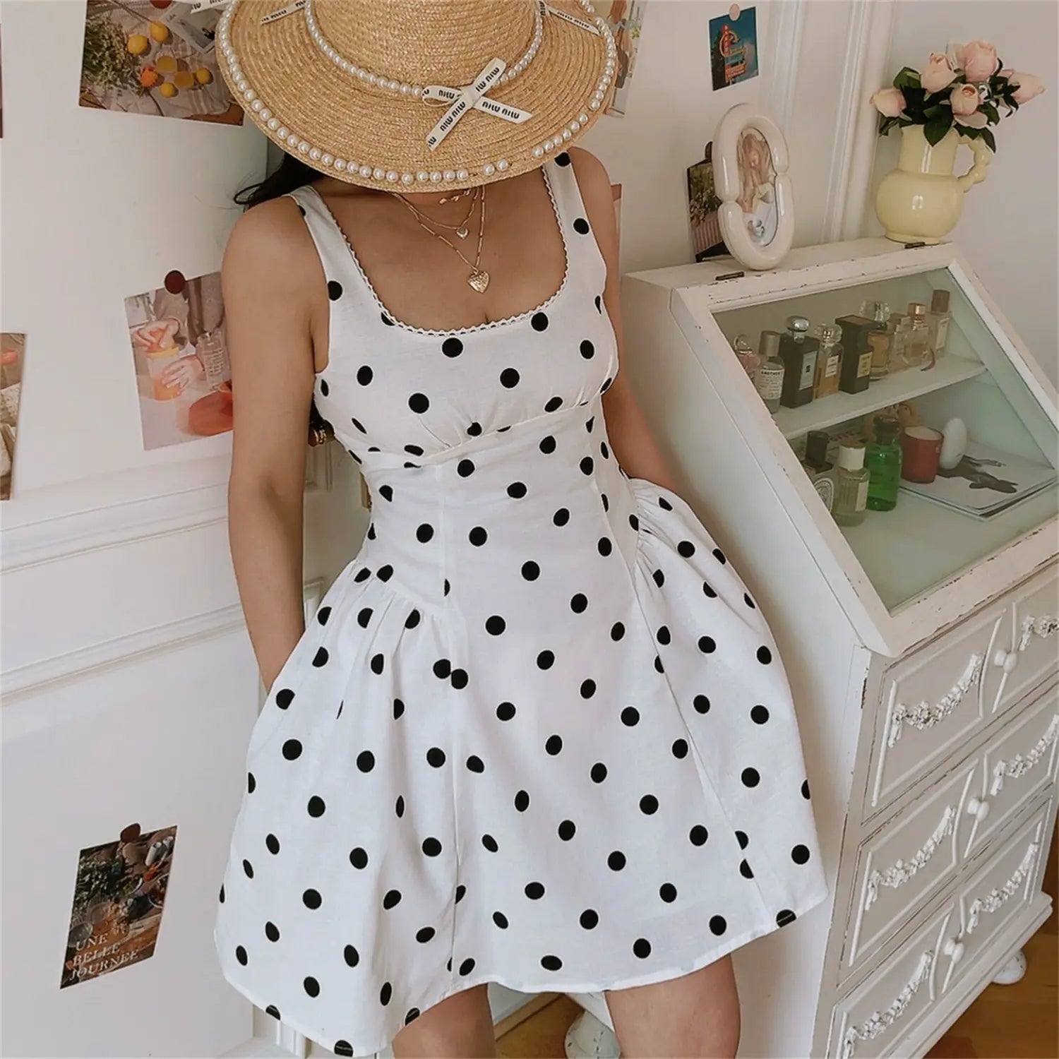 Classic white black polka dot square neck mini cami dress, lace trim neck high waisted a-line skirt, half body korean indoor model shot with hand in pocket and pearl straw hat