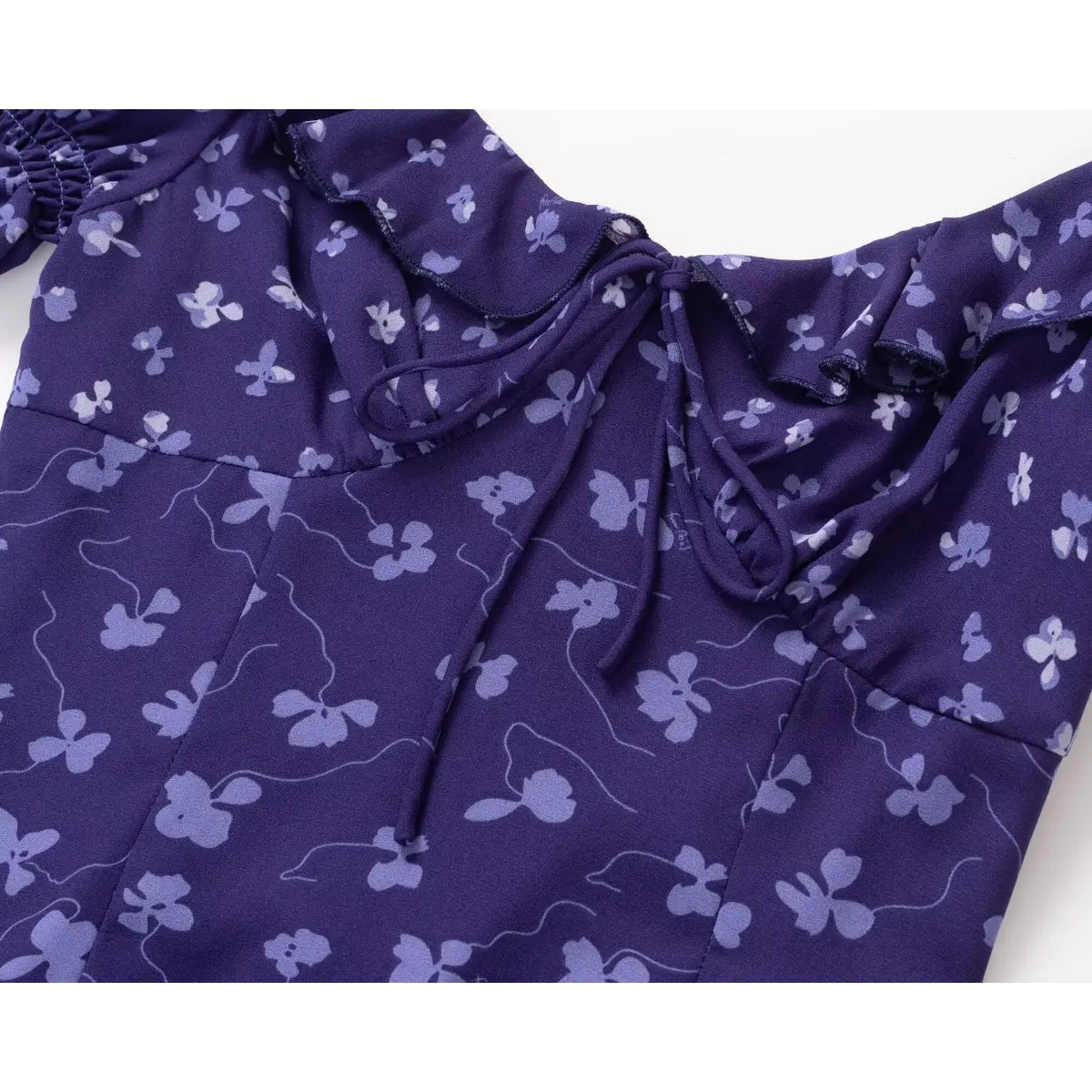 Close-up of the front tie detail on a purple floral print dress, focusing on the ruffled sweetheart neckline and gathered bust.
