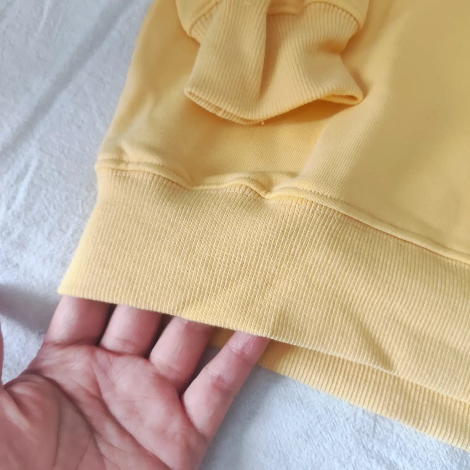 Macro shot ribbed bottom hem stitching yellow lightweight crewneck sweatshirt