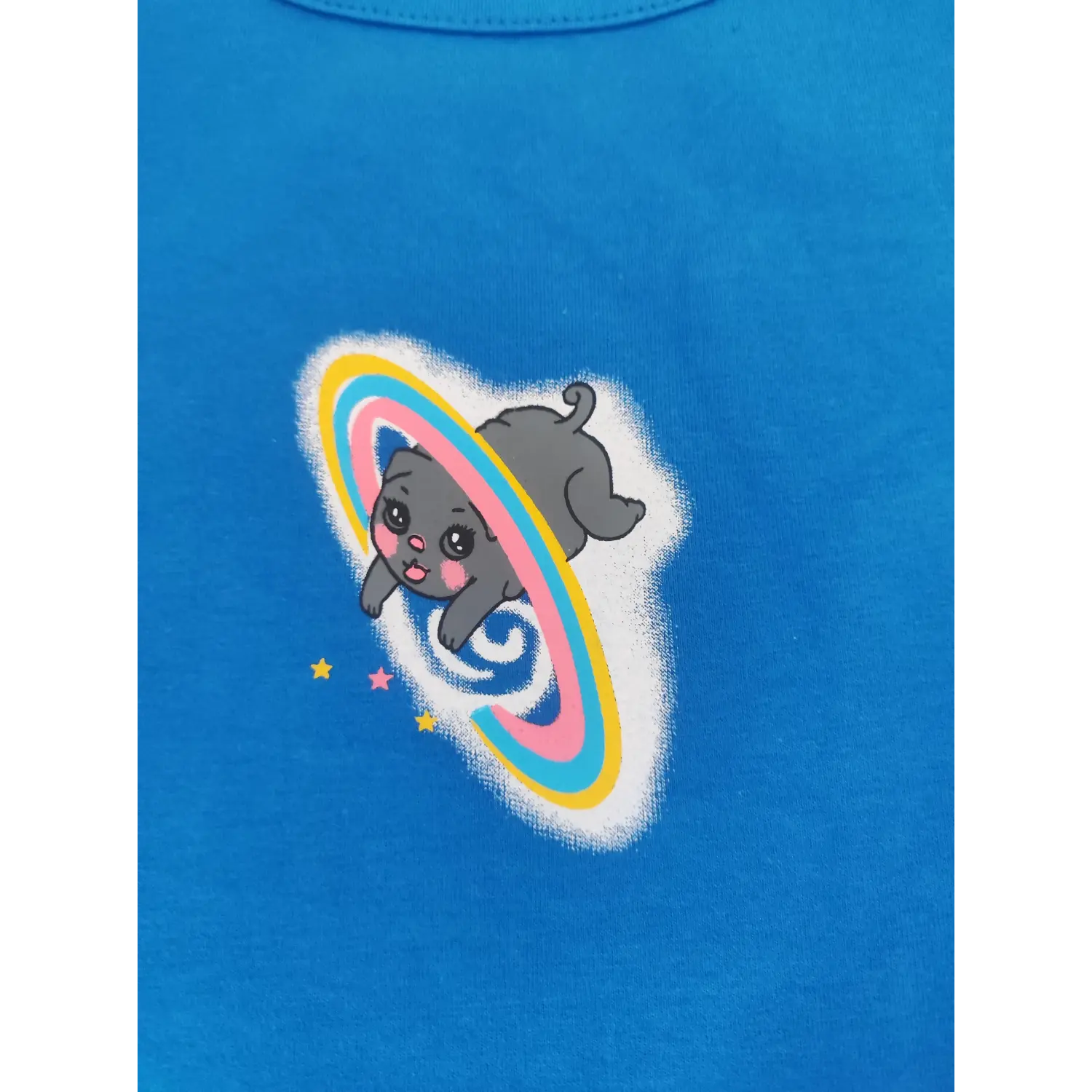 Close-up detail cute cartoon grey cat with rainbow ring planet graphic print on blue top