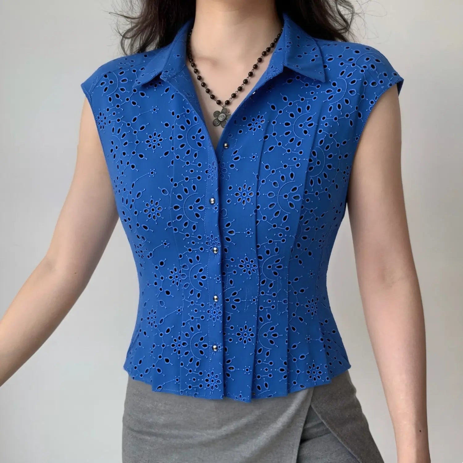Model front view wearing cobalt blue eyelet sleeveless collared shirt, casual fitted outfit