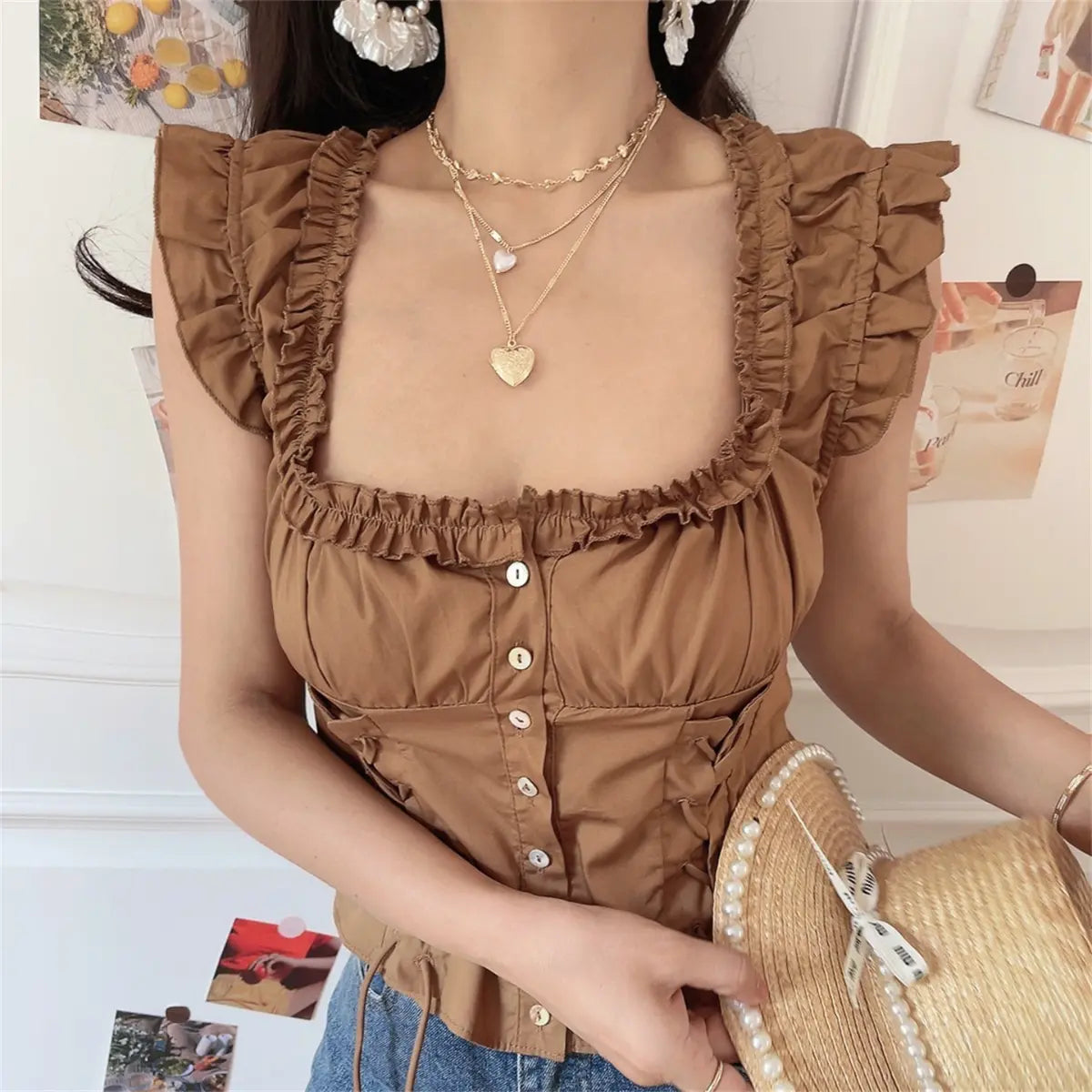 Close-up back of brown ruffle crop top with elastic shirred panel and sleeveless frilled shoulder edge.