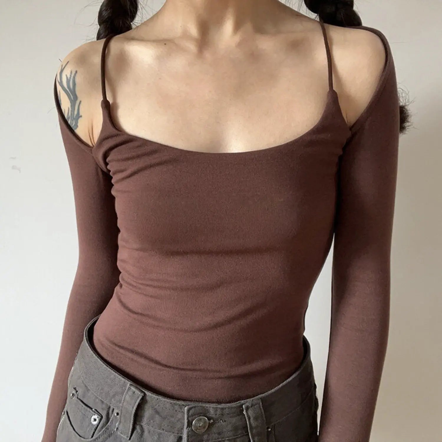 Coffee spaghetti strap fake two piece off shoulder long sleeve top front indoor model shot, square neck cold shoulder slim waist cropped stretch knit fit, matched with grey low waist pants soft feminine outfit display