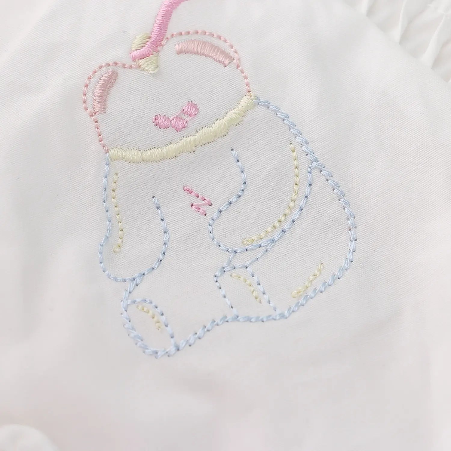 Yoke bear multi-color embroidery macro close-up, pink blue yellow thread dense full stitching smooth skin-friendly embroidery collar decor detail shot