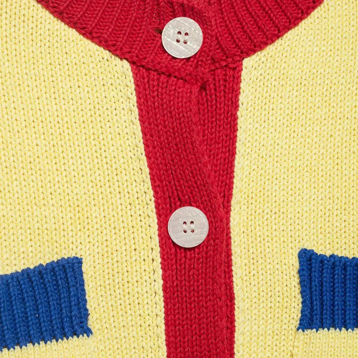 Close-up of the shell buttons on the color-block knit cardigan, showing the white iridescent buttons on the red placket