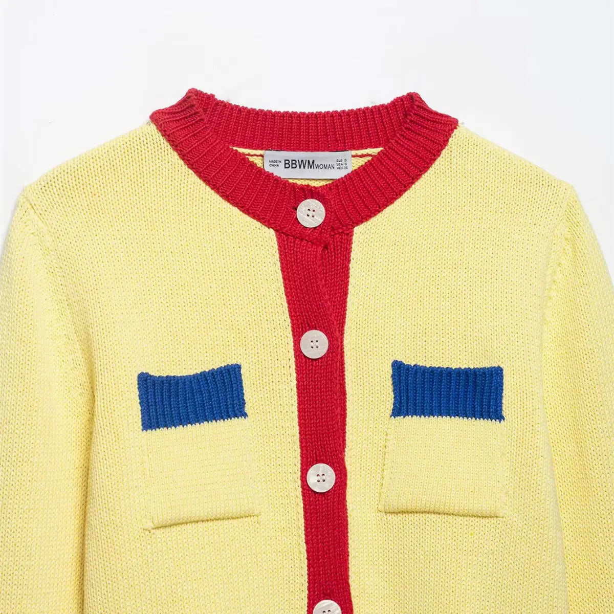 Front view of the neckline on the color-block knit cardigan, showing the red ribbed collar, shell buttons, and blue pocket tops