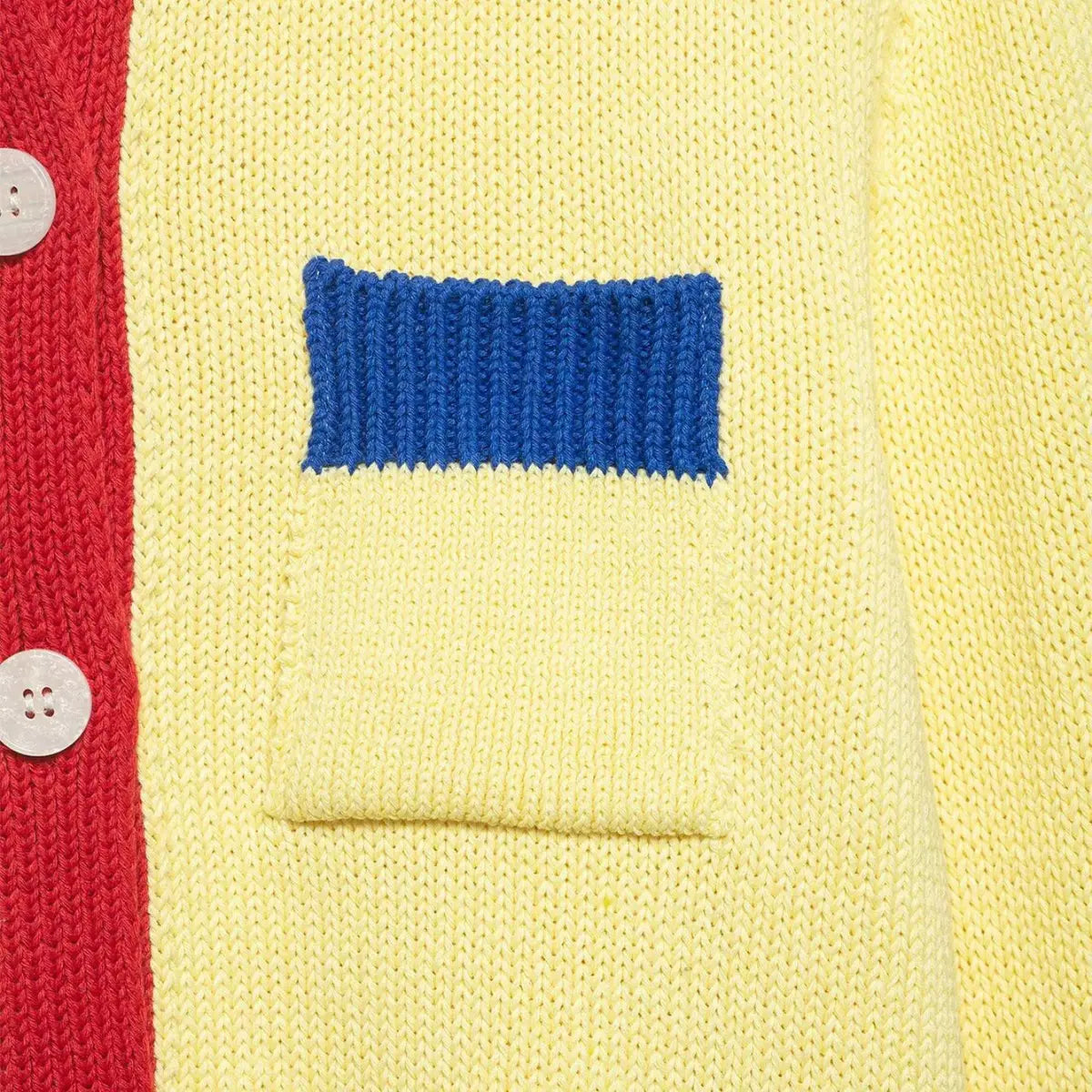 Close-up of the front pocket on the color-block knit cardigan, showing the blue ribbed pocket top and contrast red placket