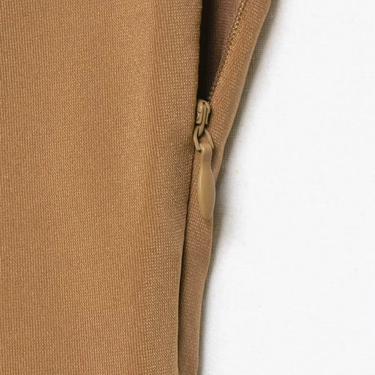 Close-up of the side zipper on the colorblock dress, showing the matching tan pull and smooth knit fabric texture
