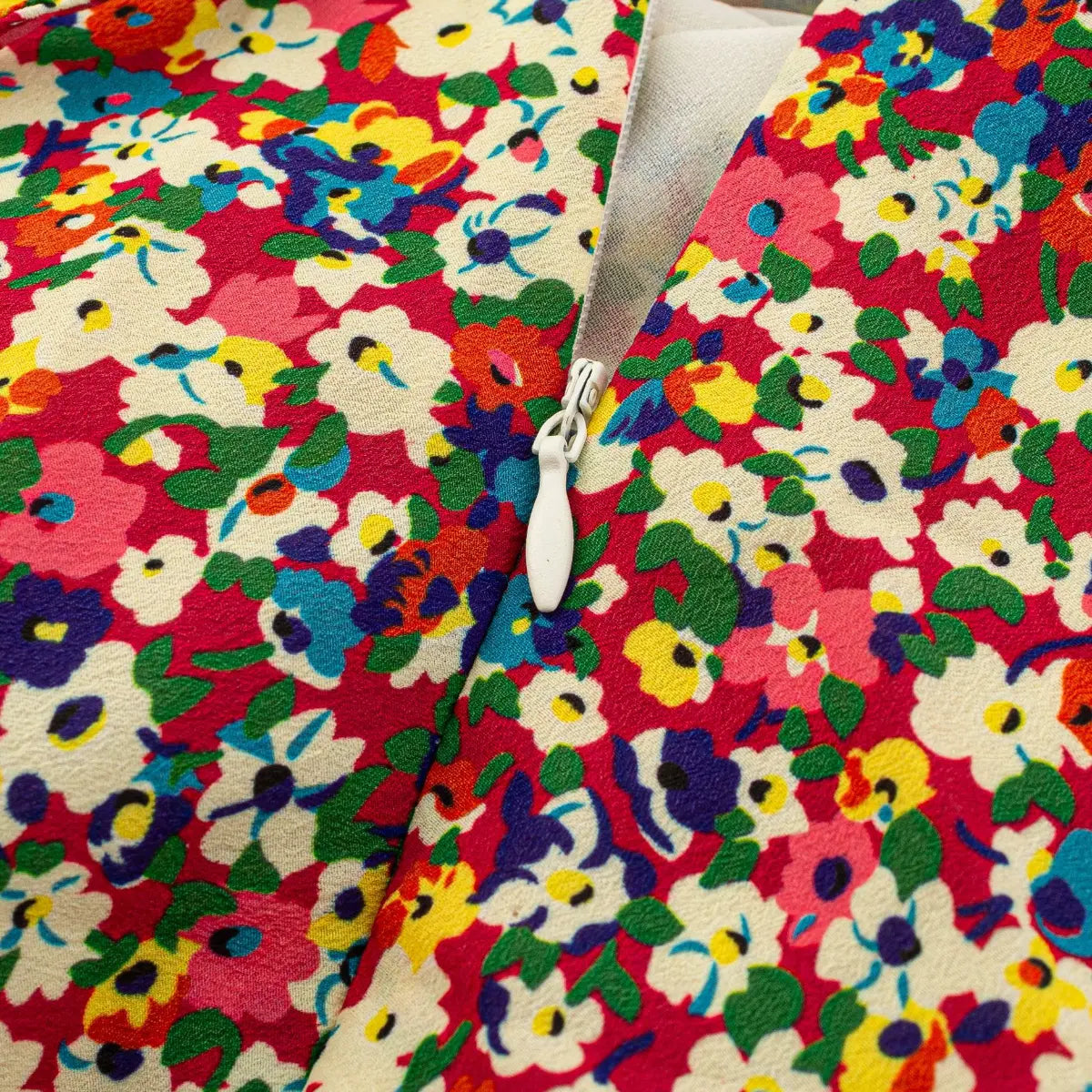 Close-up of the white side zipper on a sleeveless colorful floral print dress.
