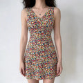 Full-body shot of a woman wearing a sleeveless colorful floral print mini dress.